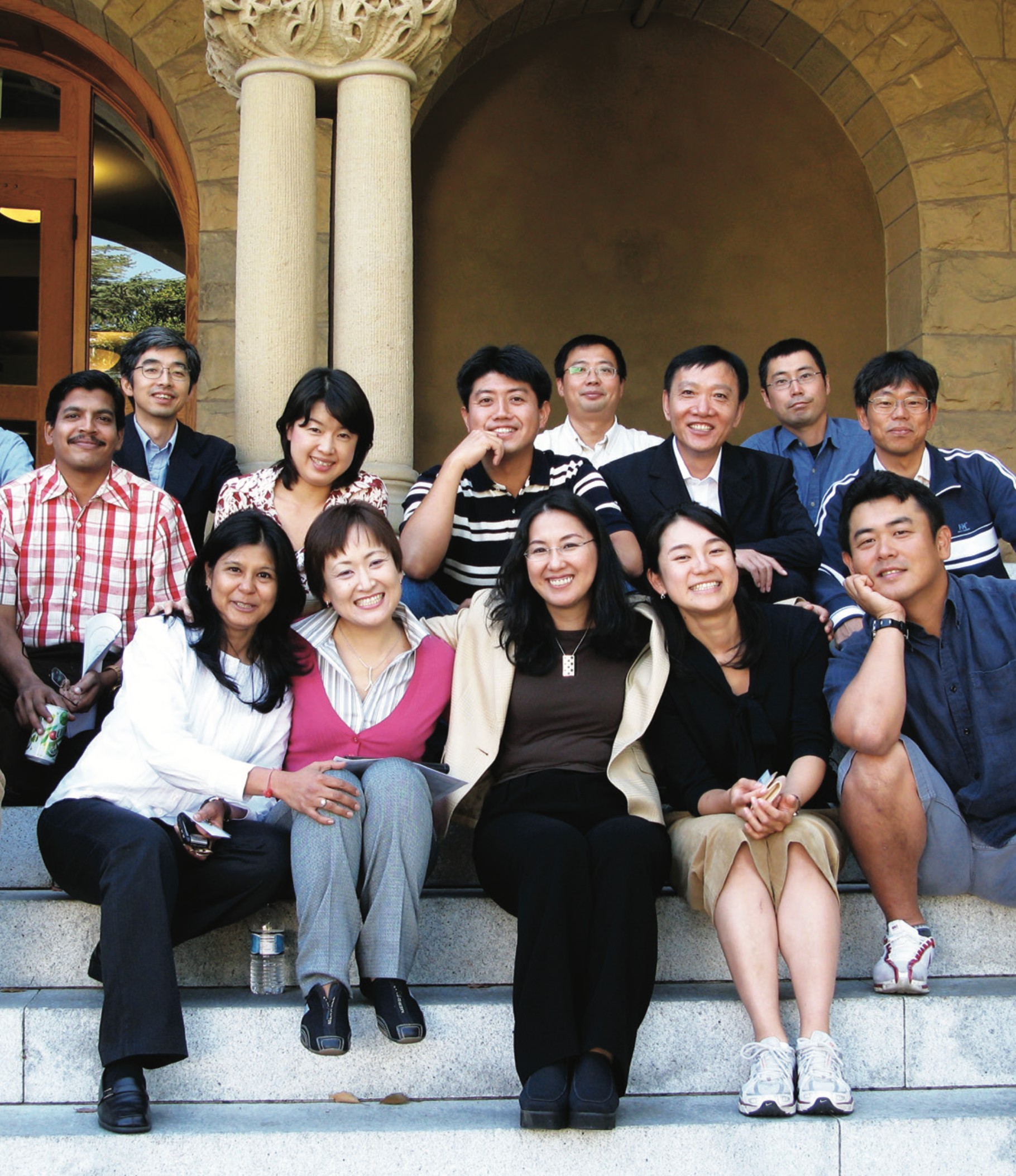 A group of people sitting on the steps at the entrace to Encina Hall, Stanford University